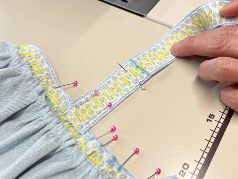 作業手順⑥ 肩ひも用のチロルリボンを、印の位置に1cm内側に差し込むように置き、待ち針でとめた様子