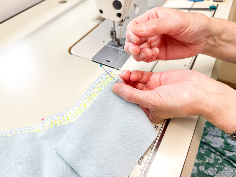 作業手順③ ②で引いたラインの上に、①で作ったスカートを乗せ、糸を引っぱってギャザーを寄せた様子。ギャザーが均等になるように調整しながら待ち針でとめる