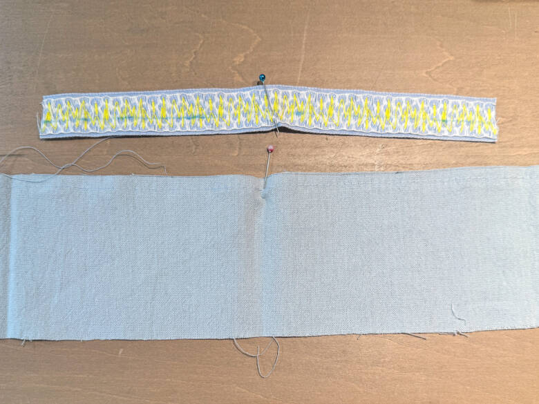 作業手順③ ②で引いたラインの上に、①で作ったスカートを乗せ、糸を引っぱってギャザーを寄せた様子。ギャザーが均等になるように調整しながら待ち針でとめる