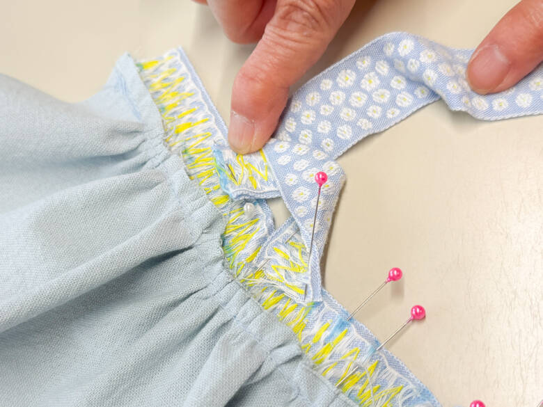 作業手順⑥ 肩ひも用のチロルリボンを、印の位置に1cm内側に差し込むように置き、待ち針でとめた様子