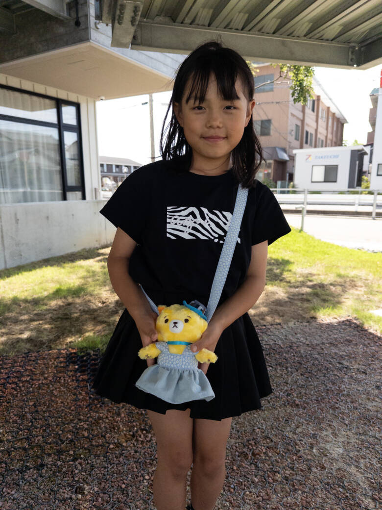手作りのぬいぐるみの服（ポシェット）を肩から下げている子ども