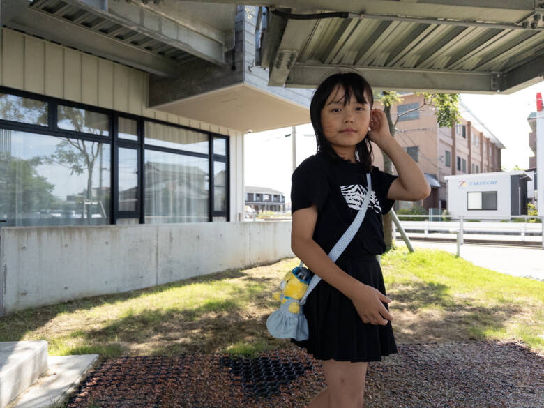 手作りのぬいぐるみの服（ポシェット）を肩から下げている子ども