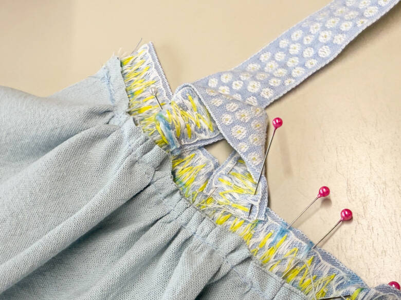 作業手順⑥ 肩ひも用のチロルリボンを、印の位置に1cm内側に差し込むように置き、待ち針でとめた様子