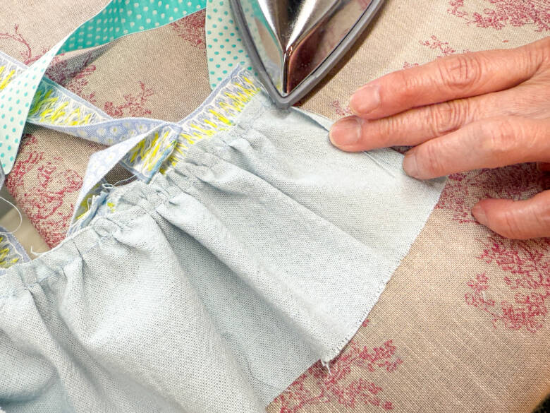 作業手順⑨ スカートの両脇は5mmの三つ折り、裾は7mmの三つ折りにして、それぞれアイロンでしっかり押さえる様子