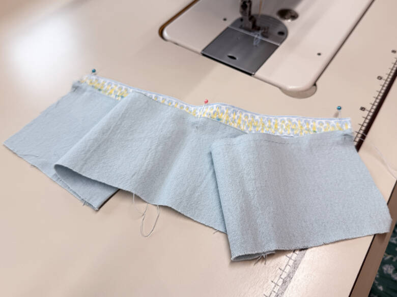 作業手順③ ②で引いたラインの上に、①で作ったスカートを乗せ、糸を引っぱってギャザーを寄せた様子。ギャザーが均等になるように調整しながら待ち針でとめる