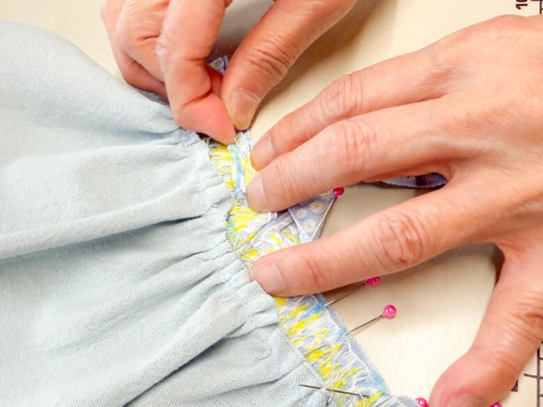 作業手順⑥ 肩ひも用のチロルリボンを、印の位置に1cm内側に差し込むように置き、待ち針でとめた様子