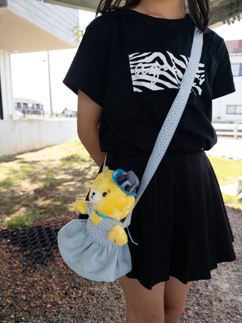 手作りのぬいぐるみの服（ポシェット）を肩から下げている子ども