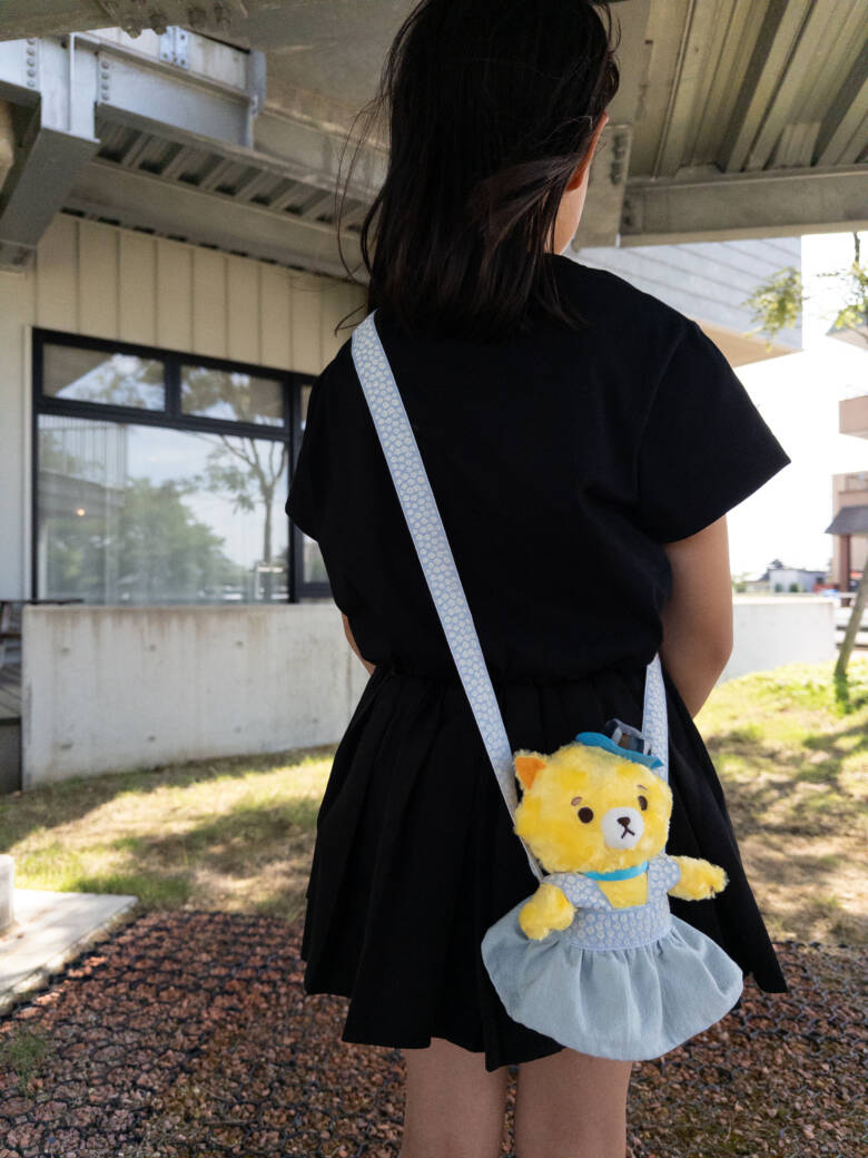 手作りのぬいぐるみの服（ポシェット）を肩から下げている子どもの後ろ姿