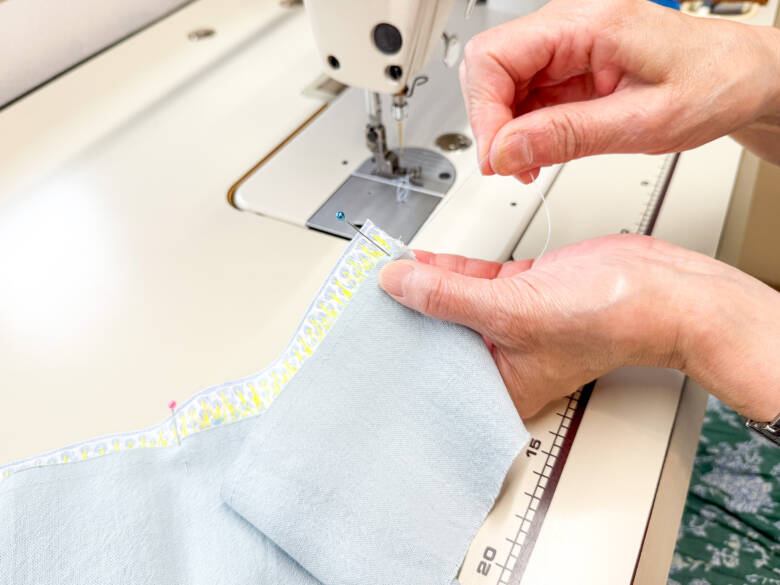 作業手順③ ②で引いたラインの上に、①で作ったスカートを乗せ、糸を引っぱってギャザーを寄せた様子。ギャザーが均等になるように調整しながら待ち針でとめる